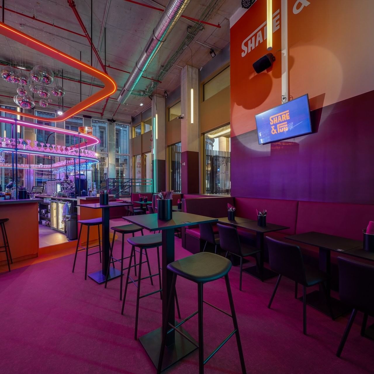 Share & Fun bar area, with stools placed by tables under neon lights and purple flooring near Warwick Grand Place Brussels