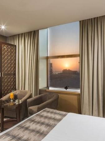 Double bed by a patterned headboard under warm spotlights in Deluxe King Sea View / Twin t Naviti by Warwick Al Khobar