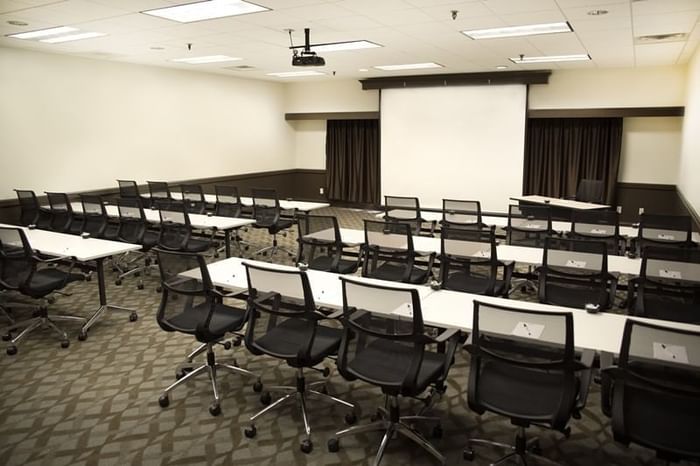 Meeting room with rows of tables and projection screen