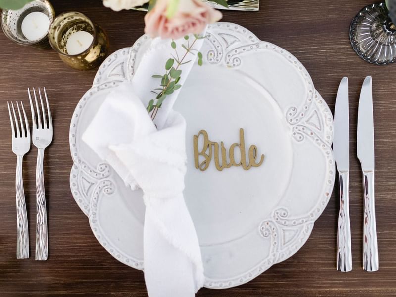 Wedding place setting featuring a gold nameplate and silverware at Grand Fiesta Americana