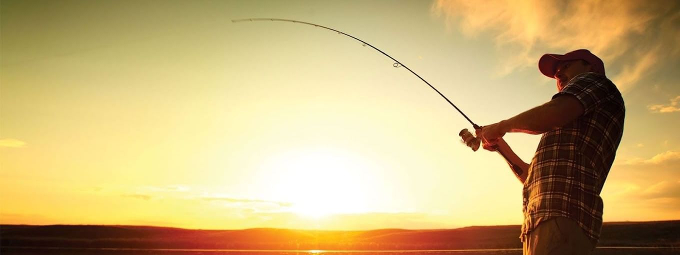 Person fishing at sunset, with a rod in hand, casting into calm waters near the Novotel Sunshine Coast Resort