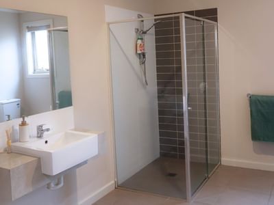 Modern bathroom with shower stall, sink, and mirror at La Trobe University Regional Housing – Melton.