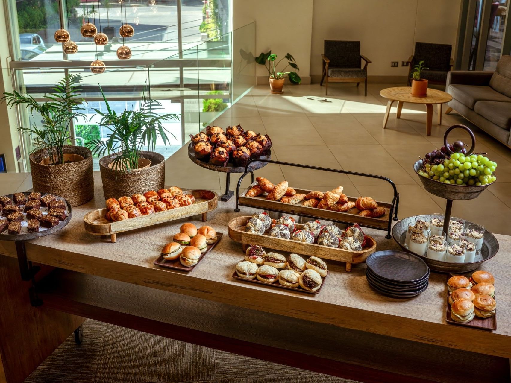 Exposición de una selección de pasteles y postres sobre una mesa de madera en el hotel HCC Costanera Concepción.
