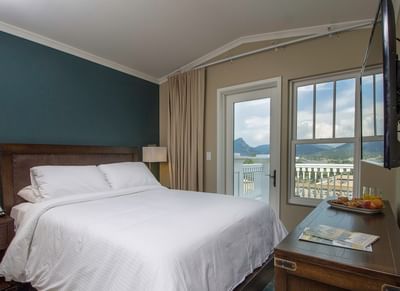 A hotel room with a queen bed, a balcony door and window with a view of the mountains at The Stanley Hotel