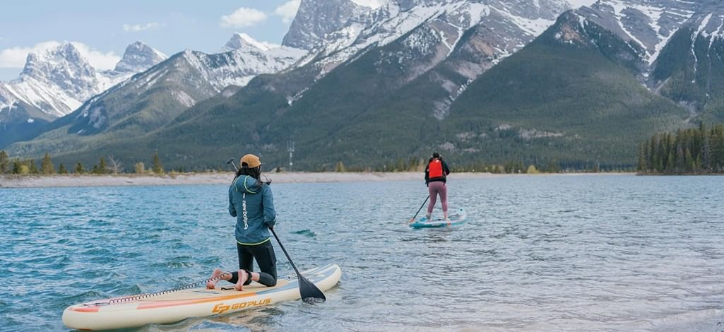 Two people paddleboard across a lake near Canmore.