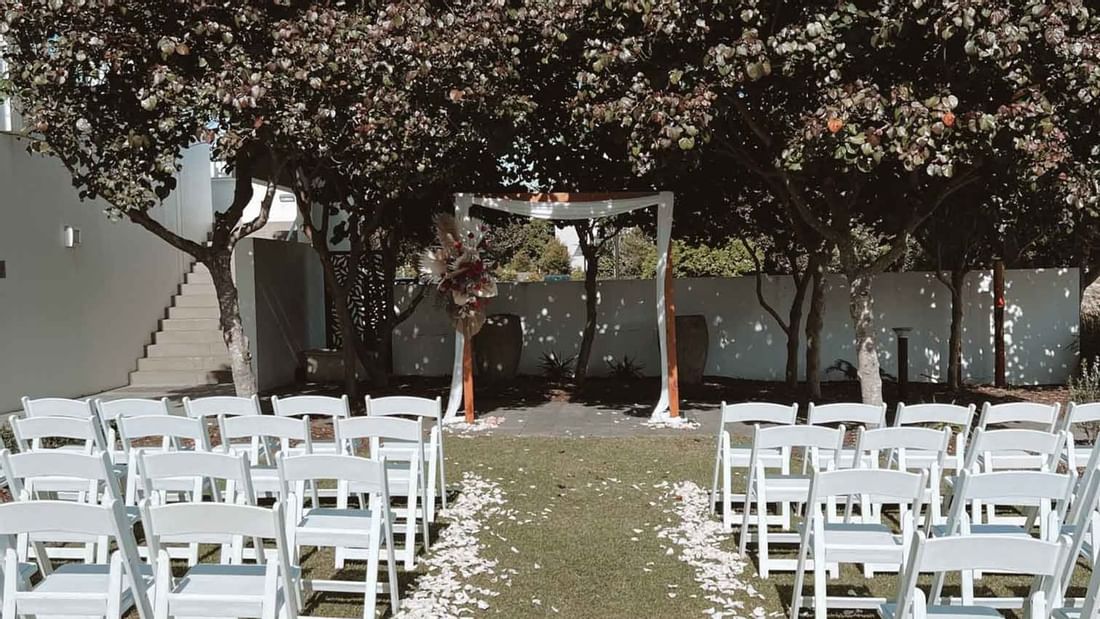 Outdoor wedding setup with white chairs at Pullman Magenta Shores