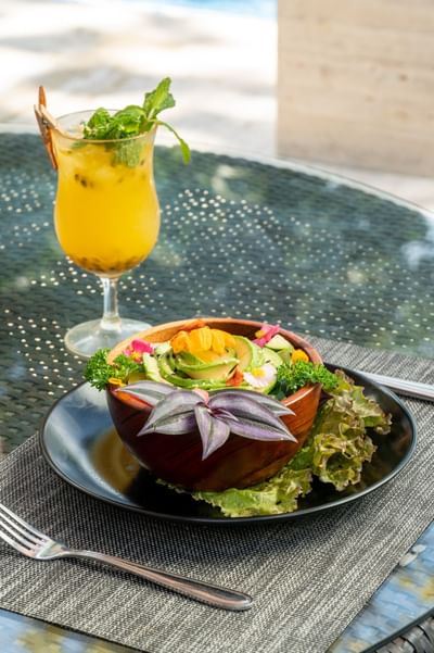 Plato de ensalada de vegetales servido con una bebida sin alcohol en Poolside Treats en Los Altos Resort