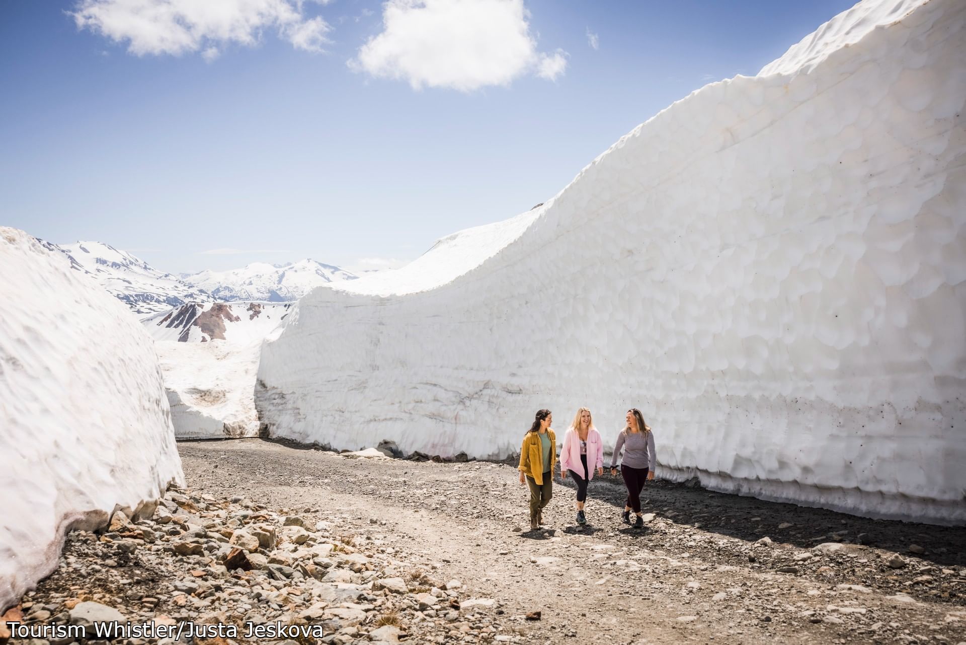 Women walking down a hill through snowy mountains near Blackcomb Springs Suites
