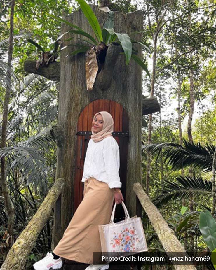 A woman was taking a picture with the charming small treehouse at Kopi Hutan - Lexis Suites Penang