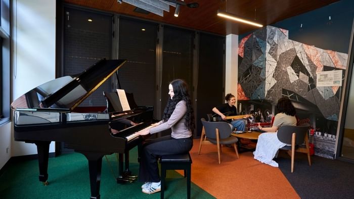People playing piano and guitar in Music Room at UniLodge Royal Melbourne North Melbourne.
