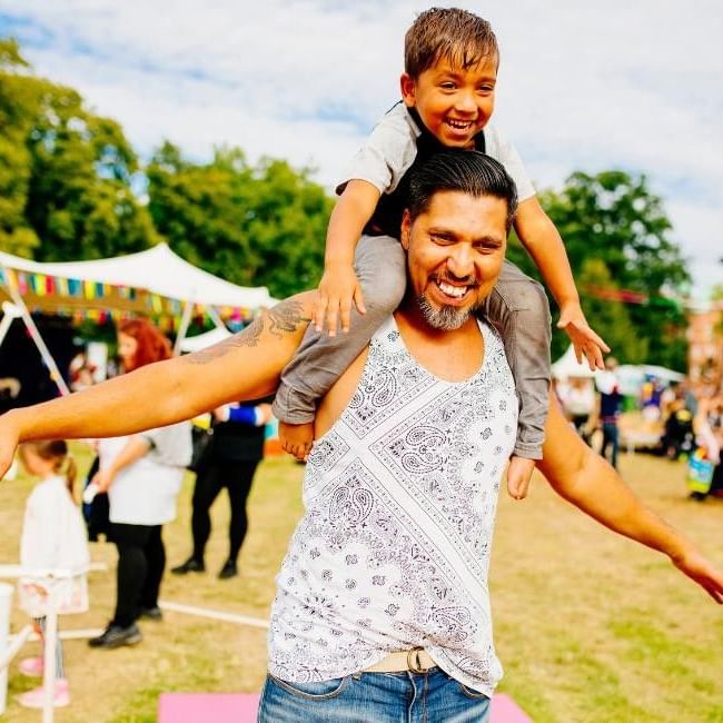 Father giving son piggyback ride featured in our article on Wokingham Party in the Park