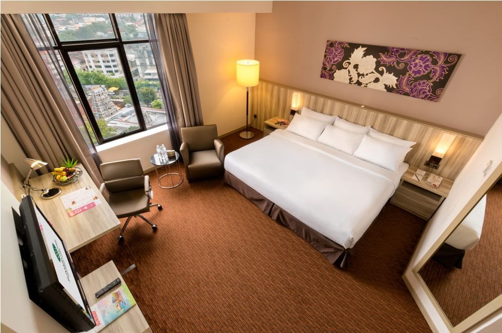 King bed with a single sofa & a TV in Deluxe King Room at Sunway Hotel Seberang Jay