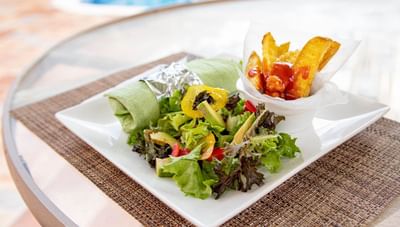 Vibrant green spinach wrap with a fresh side salad and a cup of golden fries on a patio at Worthing Court Apartment