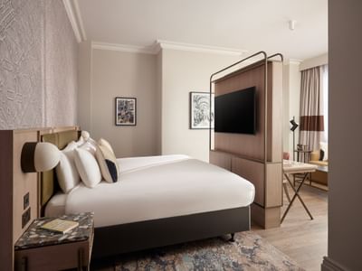 Spacious king-size bed with a wood partition and TV in a beautifully designed suite at The Met Hotel Leeds, England