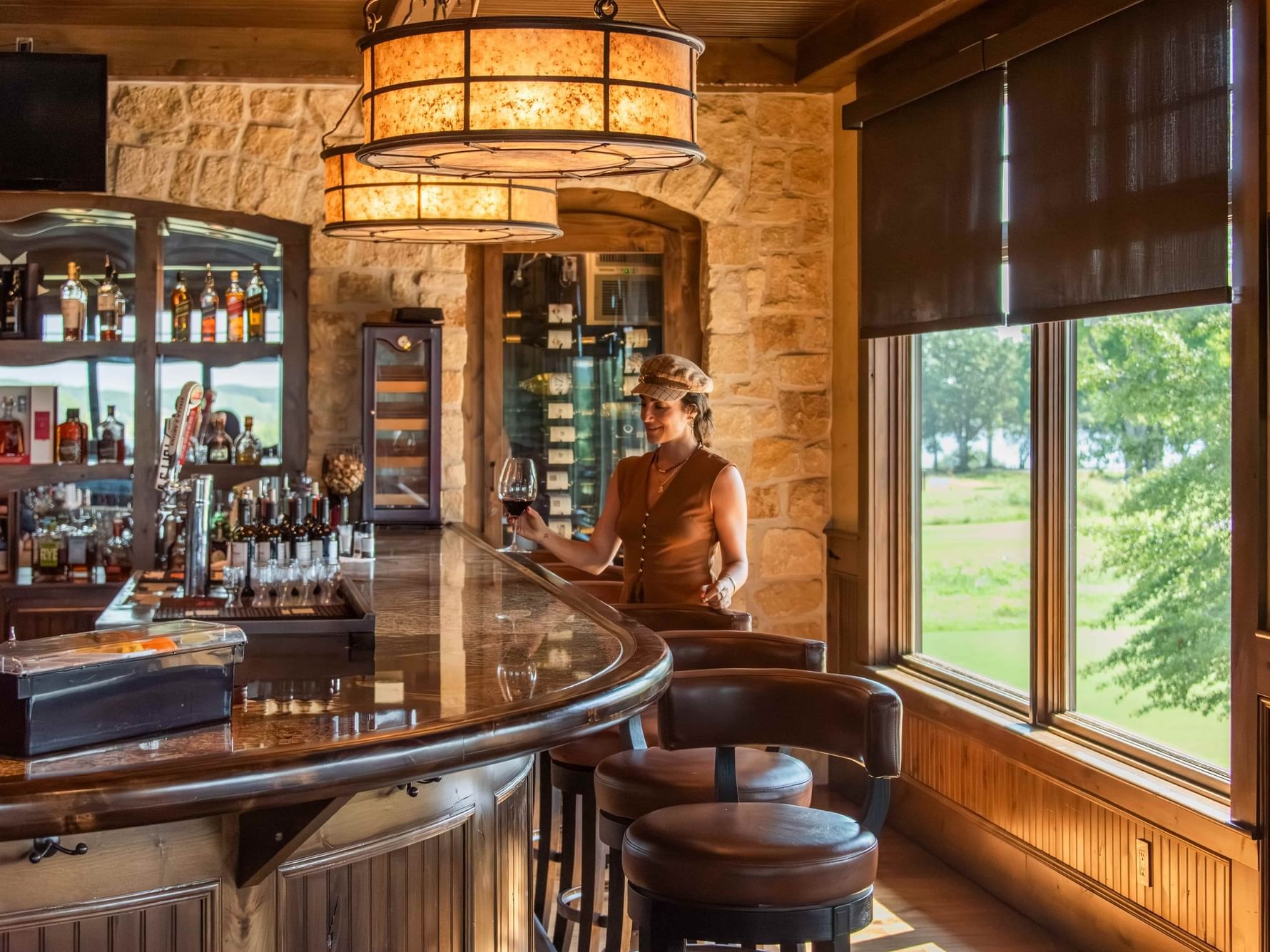 Woman holding glass of red wine at bar seating at Buffalo Bar in Shangri-La Resort and Golf Club