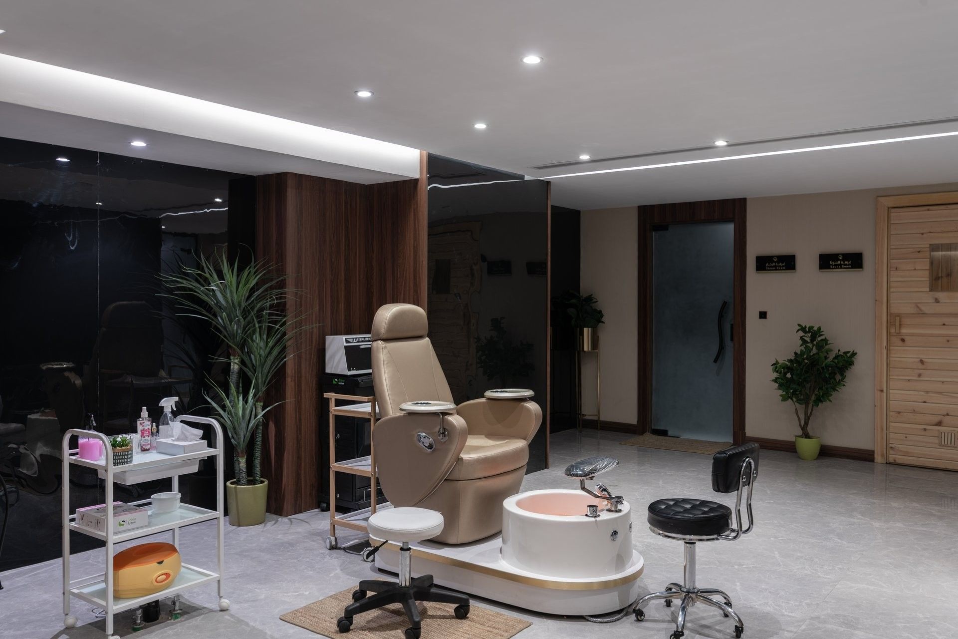 Pedicure chair by a basin and rolling stools under recessed lights in Golden Time Spa at Warwick Al Taif Hotel