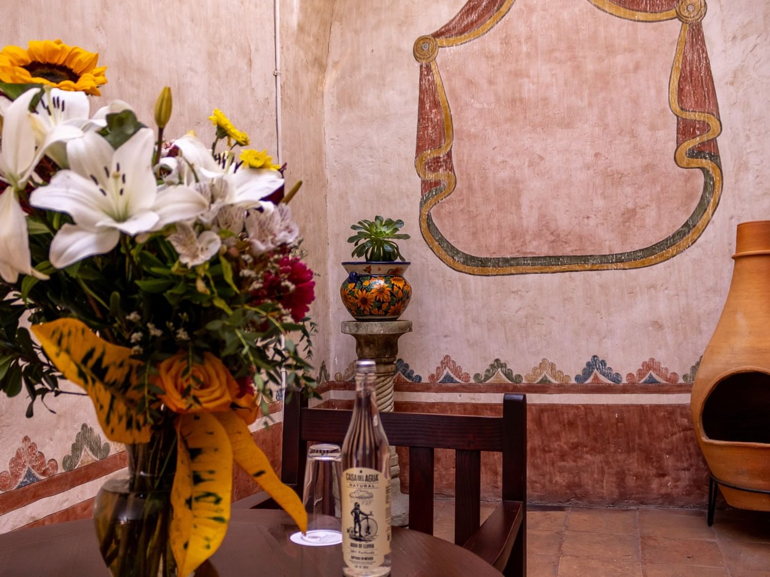 Mesa con flores y botella en Suite Gobernador King en Quinta Real Oaxaca en Oaxaca de Juárez