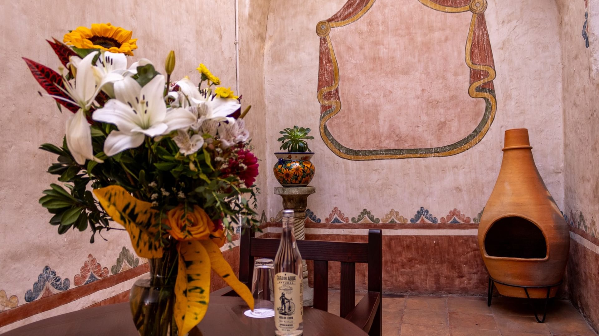 Mesa con flores y botella en Suite Gobernador King en Quinta Real Oaxaca en Oaxaca de Juárez