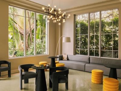 Lobby lounge with floor-to-ceiling windows, gray seating, and ottomans at Kenmore Village Hotel, Best South Beach hotels