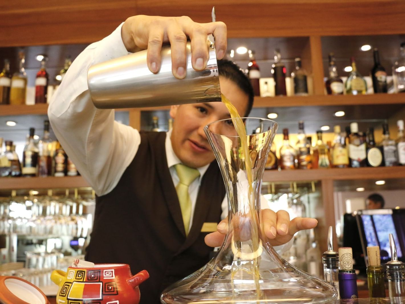 A bartender poring the cocktail to a glass at Hotel Sumaq 