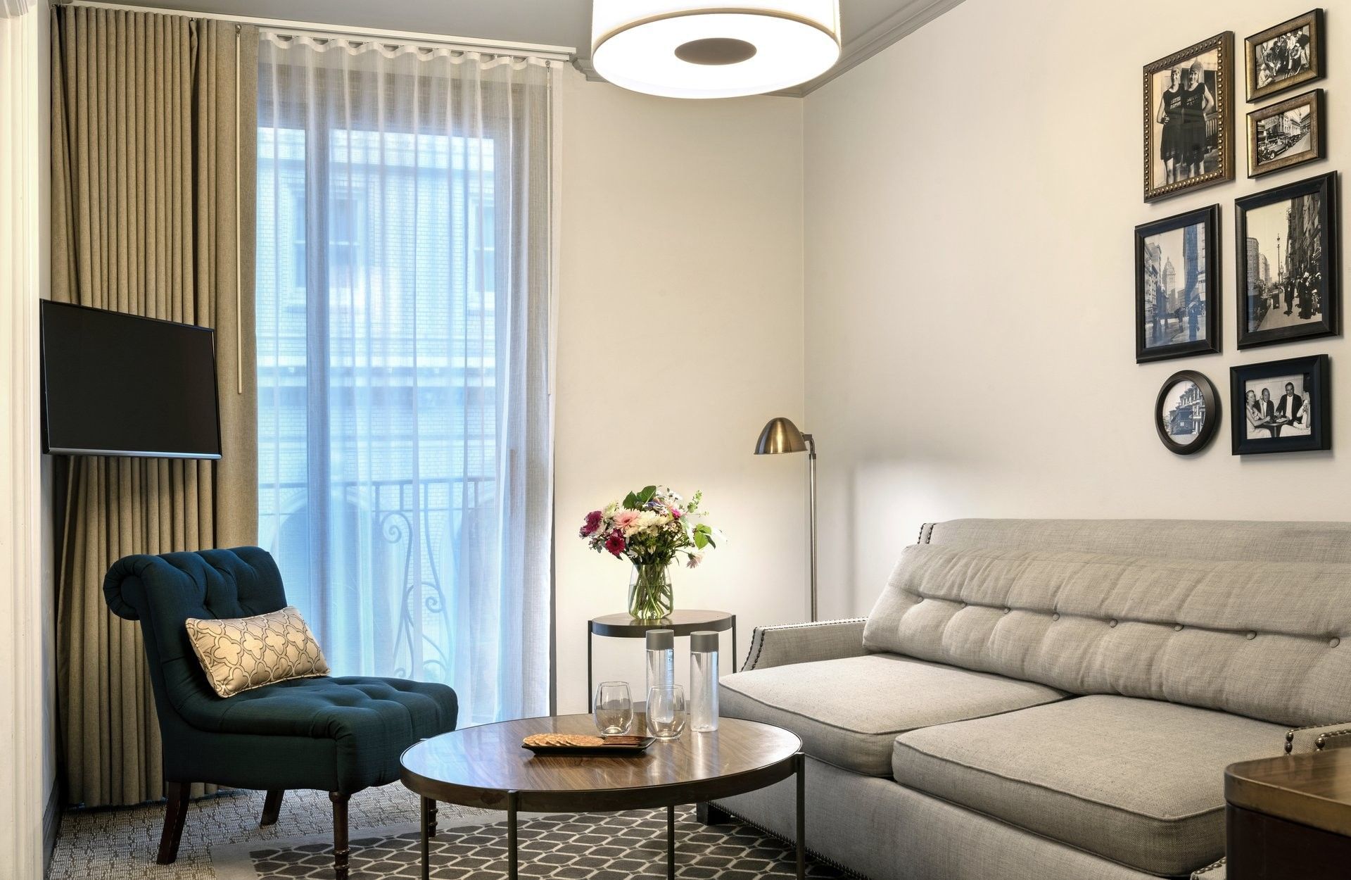 Teal armchair by a small round table under a floor lamp near a gallery wall in Suite at Warwick San Francisco