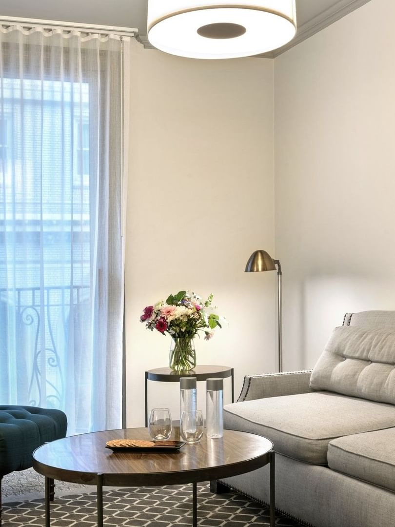 Teal armchair by a small round table under a floor lamp near a gallery wall in Suite at Warwick San Francisco