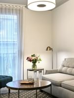 Teal armchair by a small round table under a floor lamp near a gallery wall in Suite at Warwick San Francisco