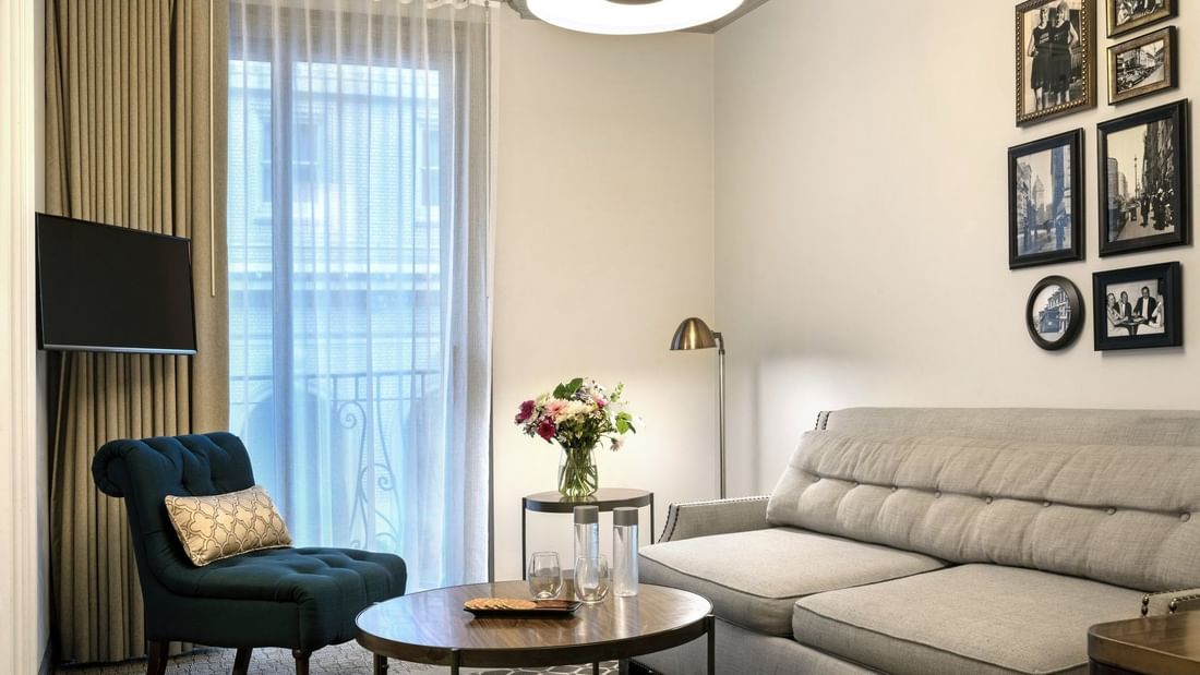 Teal armchair by a small round table under a floor lamp near a gallery wall in Suite at Warwick San Francisco
