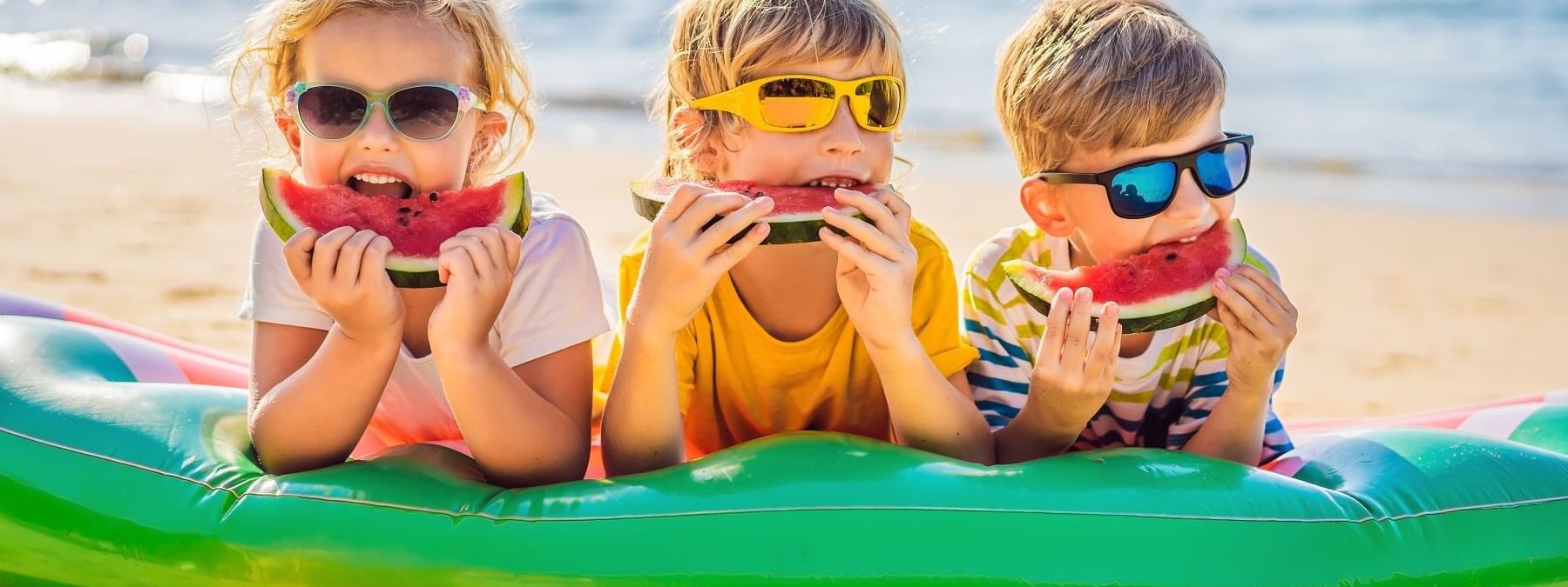 Kids eating watermelon on beach at Daydream Island Resort