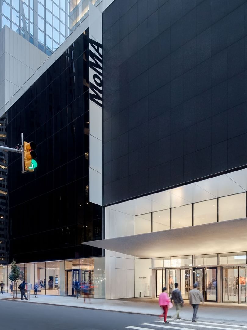Glass and dark stone facade of the MoMA entrance by a city street near Warwick New York