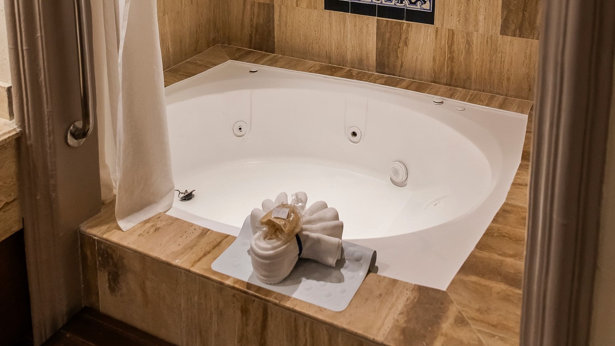 White jetted tub with decorative towel arrangement and wood accents in King Grand Class at Quinta Real Zacatecas