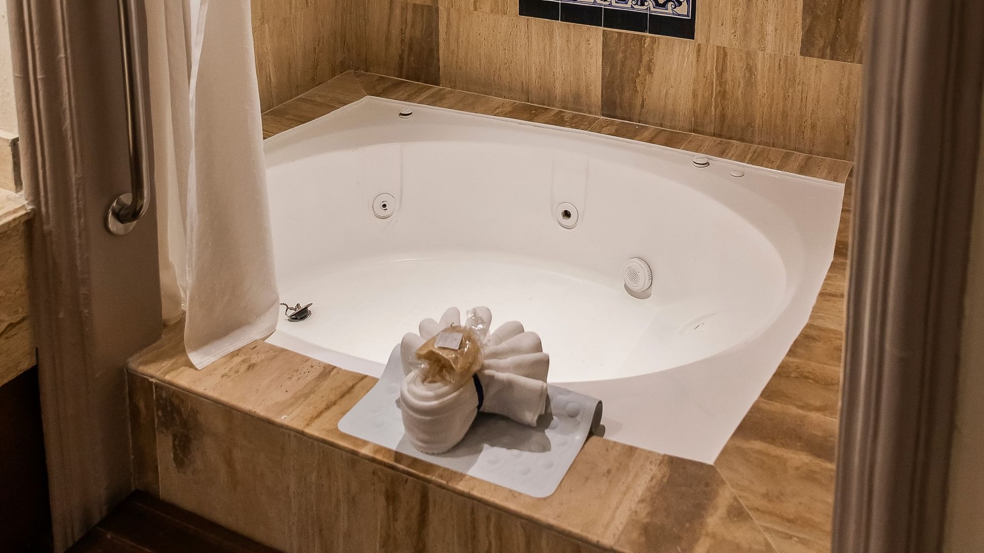 White jetted tub with decorative towel arrangement and wood accents in King Grand Class at Quinta Real Zacatecas