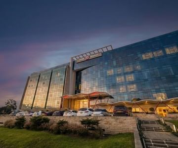 Modern glass building exterior with glowing lights under an evening twilight purple sky at Hotel B3 Sibelius
