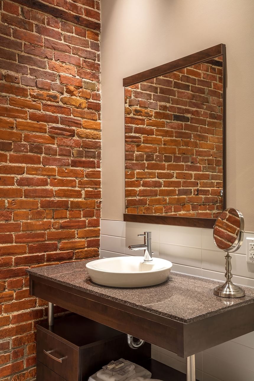 exposed brick wall in a bathroom with a sink and mirror