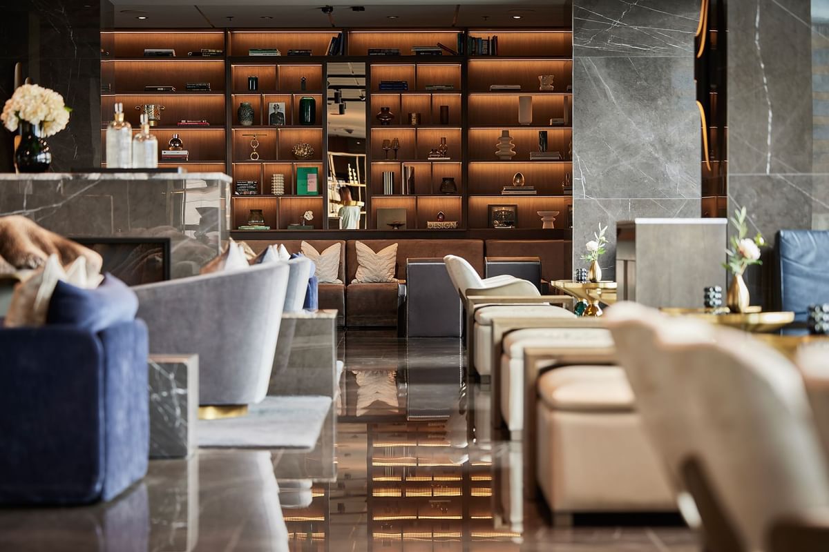 Elegant lobby med moderna möbler, öppen spis, och ett stort bokhyllsystem med dekorativa föremål.