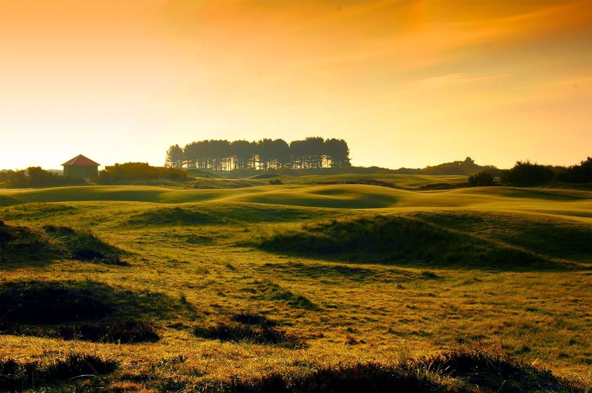 Sunset over a serene golf course with undulating hills and trees at Golf Hotel St Andrews Scotland