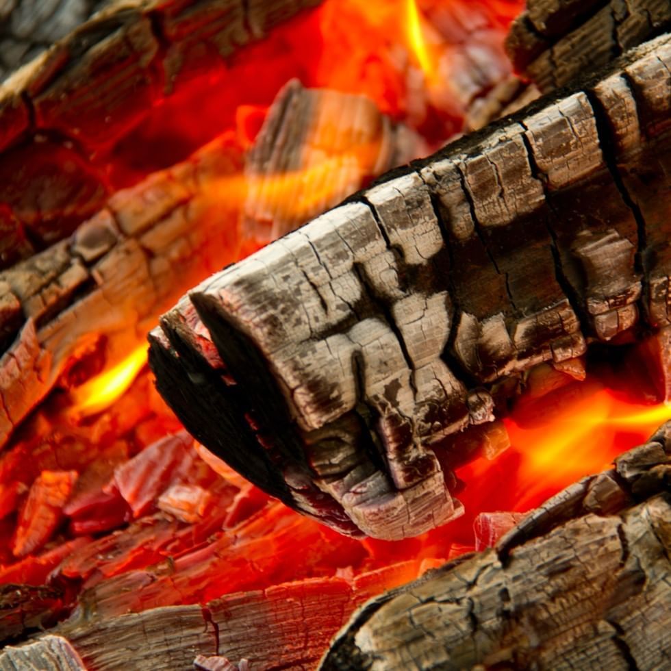 Close-up of glowing embers and charred wood in a fire near Falkensteiner Club Funimation Garden Calabria