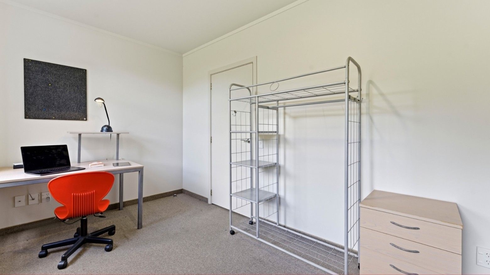 Desk with laptop, red chair, metal shelving, and wooden cabinet in a room at UniLodge Stafford House.