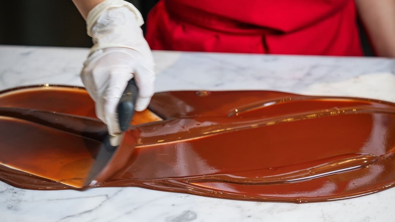 Chef in a red apron tempering chocolate on a marble slab at Paramount Hotel Dubai