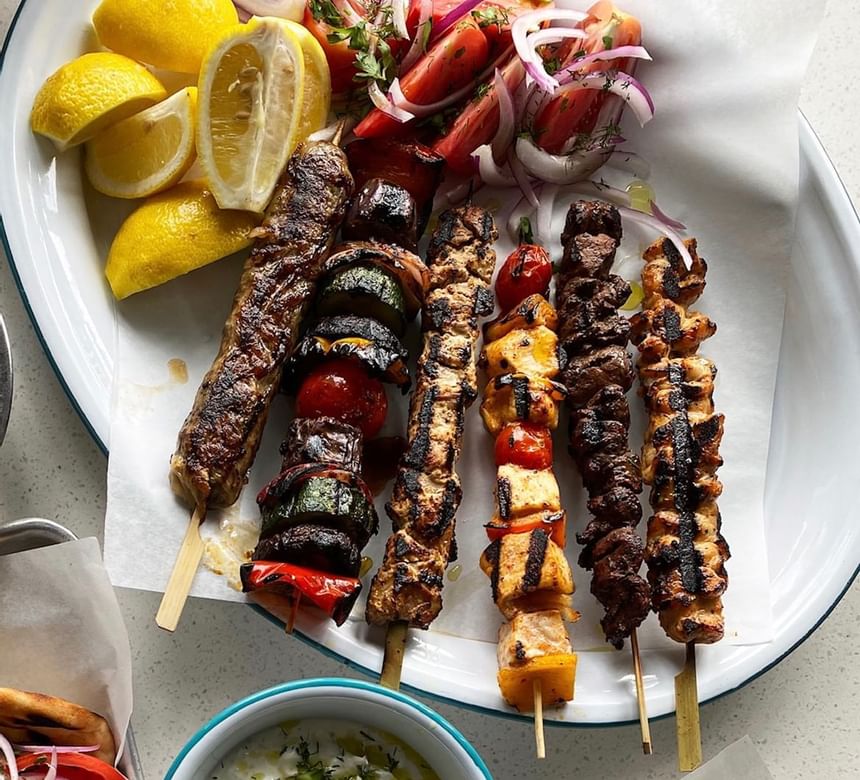 Image of a variety of kebabs with lemon and tomatoes