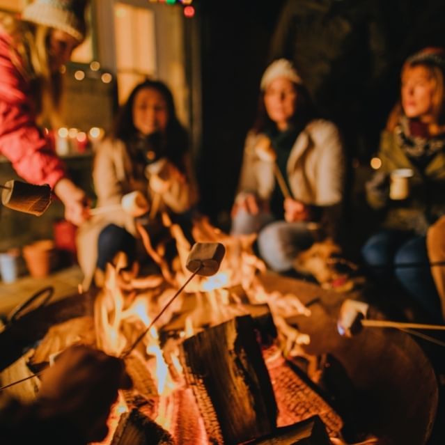 Peoples roasting marshmallows over firepit at Chase on The Lake