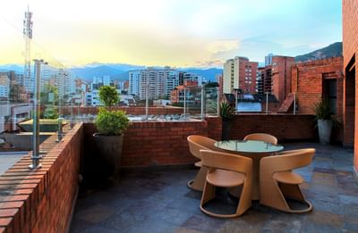 Suite Majestic rooftop terrace featuring a glass table and woven chairs, with a panoramic view at Dann Carlton Cali
