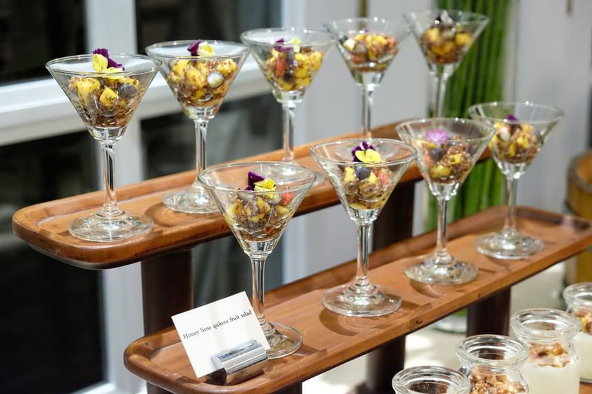 Tray with martini glasses filled with honey lime quinoa fruit salad, garnished with edible flowers at Park Hyatt Saigon