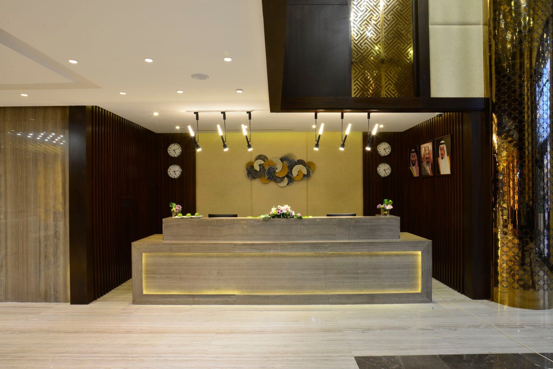 Reception desk by gold wall art under spot lighting in the lobby at Naviti By Warwick Dammam