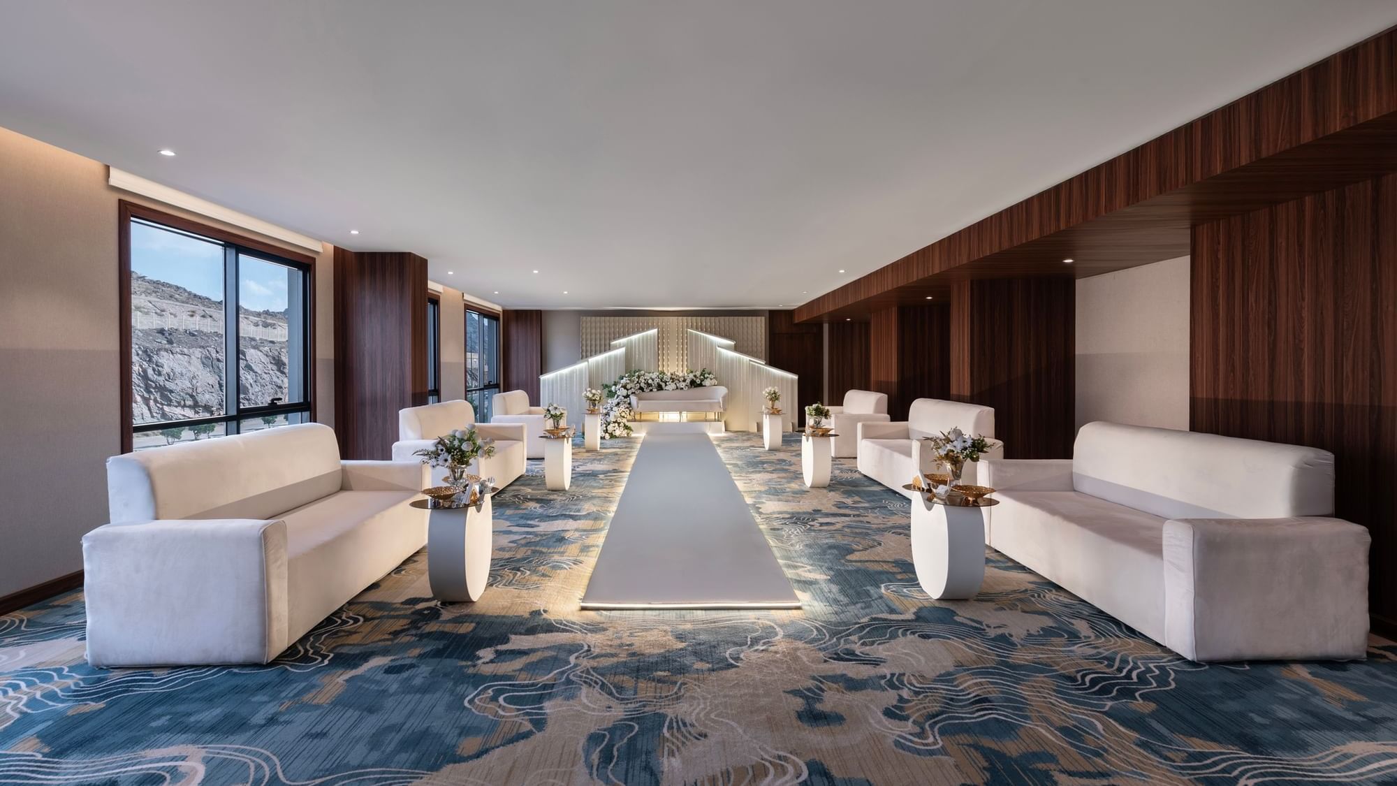Elegant indoor wedding setup with a white runway, flanked by cream chairs in Amarige Hall at Warwick Hotels and Resorts