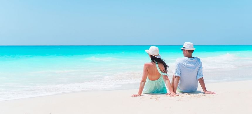 Couple in hats, embracing the charm of a luxury small adults-only hotel Barbados with ocean views near The Abidah Hotel