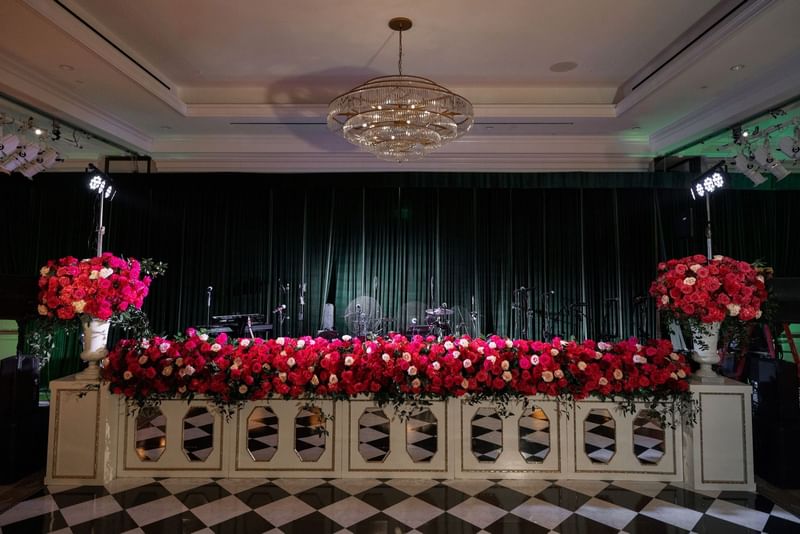 Pink roses in a long row by a checkered floor under a crystal chandelier at Warwick Melrose Dallas
