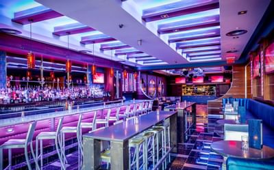 Chic bar counter with stools and tall tables extending through Harborside Bar and Lounge at Harborside Inn Boston
