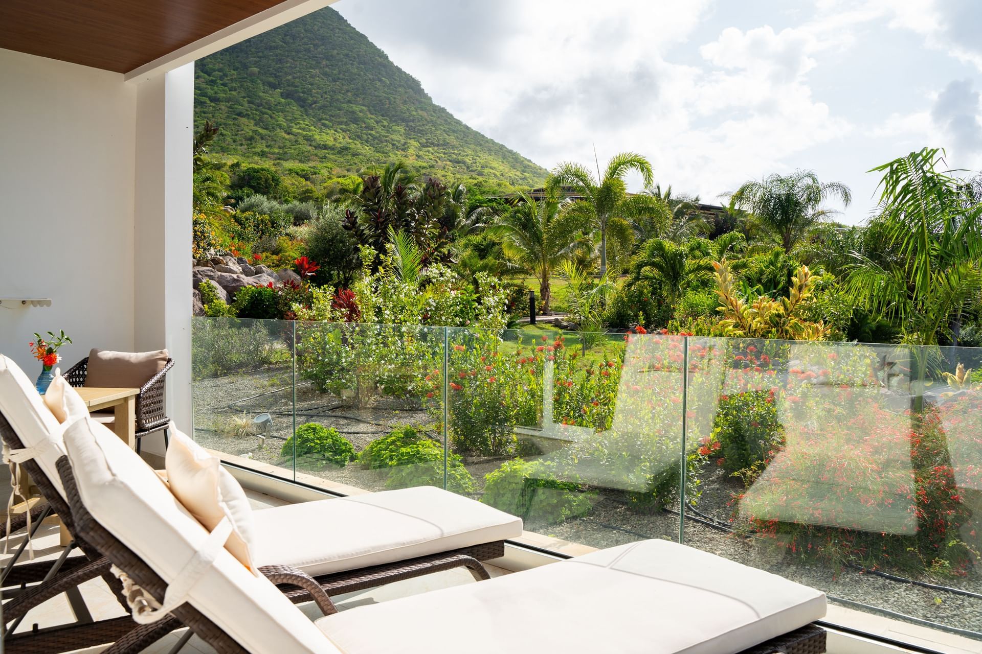 Balkon met twee ligstoelen met uitzicht op weelderige tuin en bergen in Deluxe Ocean View Room bij Golden Rock Resort
