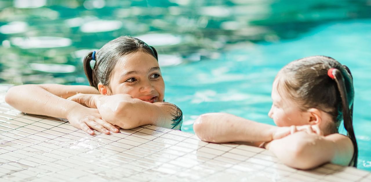 two kids resting on the side of the pool